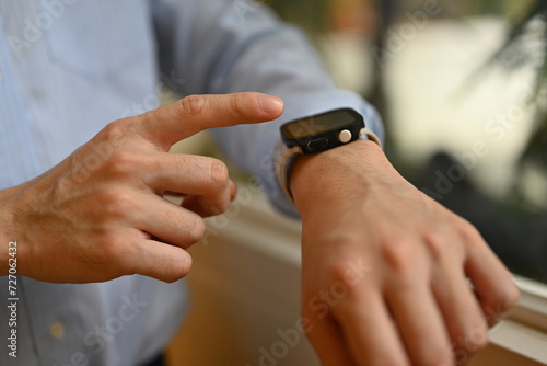Cropped image with an unrecognizable businessman's hand touching on smartwatch