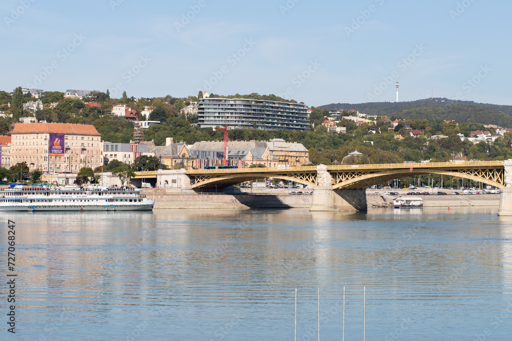 Walking bridge in Budapest. Sunny weather and modern buildings in the capital. Danube river in a big city.