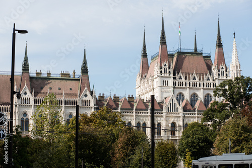 The tall spiers of the Parliament in Budapest. Capital of Hungary. The main attraction of Europe. Beautiful facade of the Parliament building. Burgundy roof of the building. Gothic style in architectu