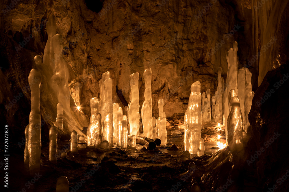 Fotografie Ice stalagmites in a cave illuminated by candles
