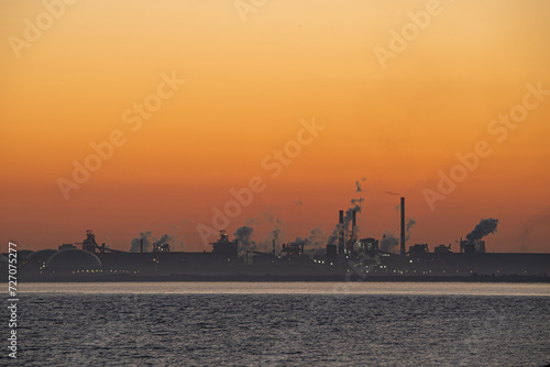 Silhouettes of factories at dawn and smoke coming from chimneys in industrial complexes 