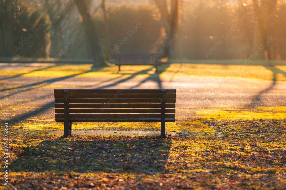 Empty park bench with blurred lit background. Autumn in the park. Dreamy, glow effect