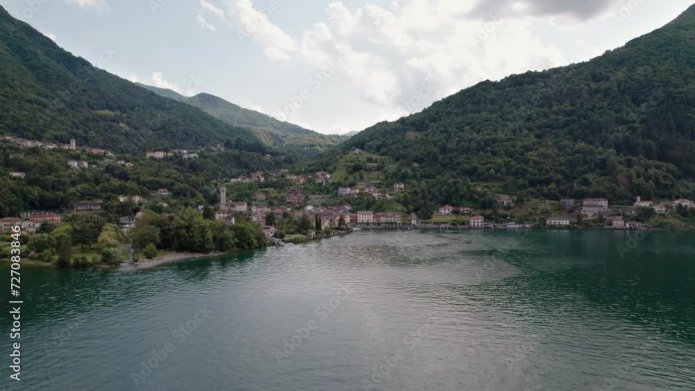 Drone flies over the lake and you can see the small fishing village of Osteno in Italy. Breathtaking scenery on a beautiful summer day. Pan camera movement from left to right Drone flies over the lake and you can see the small fishing village of Osteno in Italy. Breathtaking scenery on a beautiful summer day. Pan camera movement from left to right