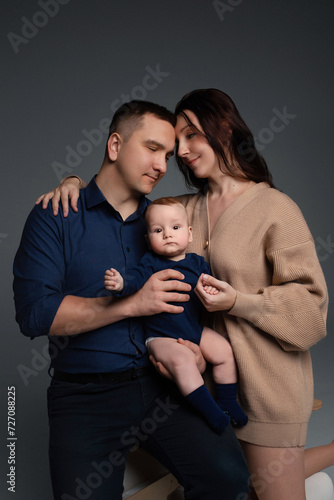 close-up portrait of happy parents hugging their little son in their arms. photograph on a dark background. happy family concept. young father and mother with baby