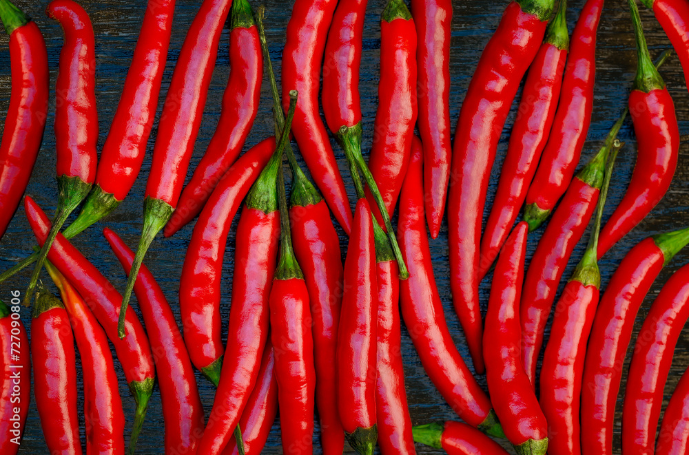 Abstract food background, top view many red hot chili pepper on  dark wood background.