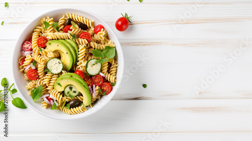 Healthy Chicken Pasta Salad with Avocado Tomato and olive oil and vinegar dressing in white bowl on white wood table vertical view from above free space. Creative Banner. Copyspace image 