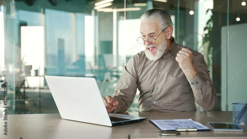 Happy senior gray haired businessman received great news on laptop computer sitting in business office. Excited smiling mature entrepreneur reads pleasant message, celebrates success, rejoices at win Happy senior gray haired businessman received great news on laptop computer sitting in business office. Excited smiling mature entrepreneur reads pleasant message, celebrates success, rejoices at win