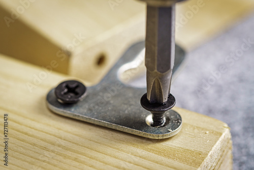 Screwing a furniture hanger to a board with a self-tapping screw