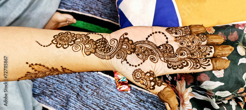 Beautiful artwork drawn on the hand of an Indian bride with herbal heena in wet condition. photo