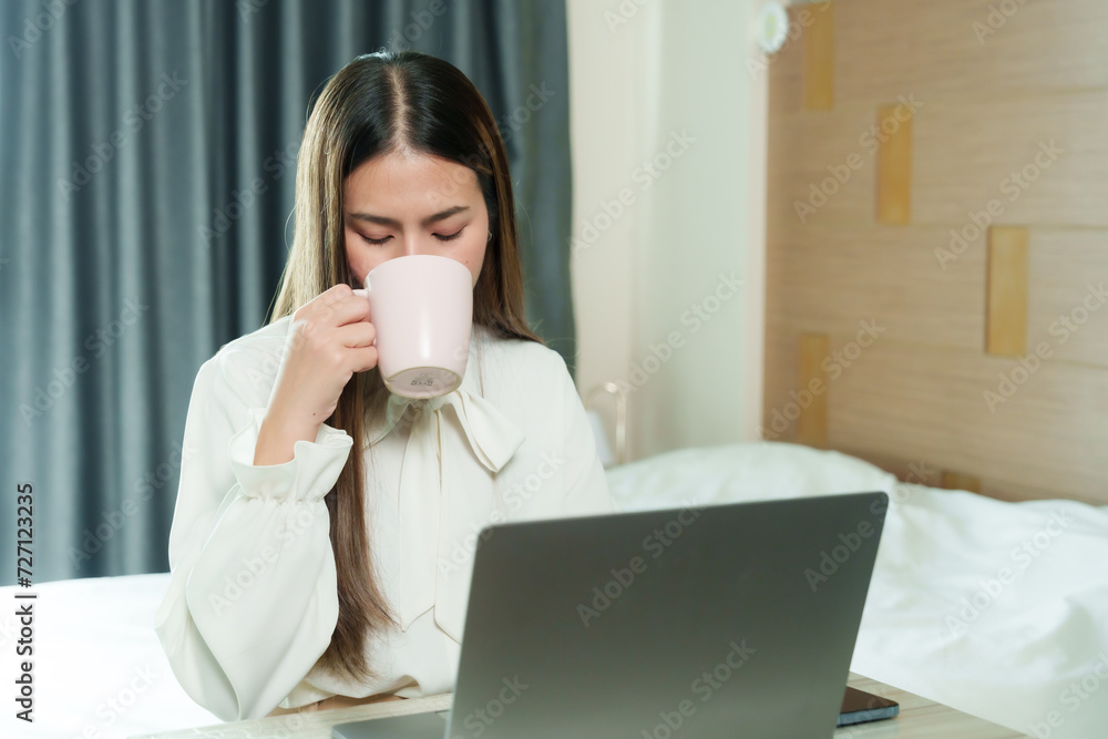 Pensive young woman sips coffee while gazing at her laptop, blending a moment of reflection with productivity. female adult enjoys a cup of coffee during a thoughtful work break on her laptop Pensive young woman sips coffee while gazing at her laptop, blending a moment of reflection with productivity. female adult enjoys a cup of coffee during a thoughtful work break on her laptop