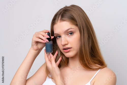 Teenager Russian girl isolated on white background holding a serum. Close up portrait