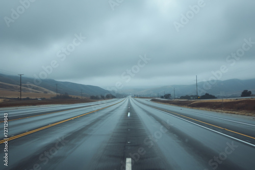 A gray cloudy sky with long stretch of highway.