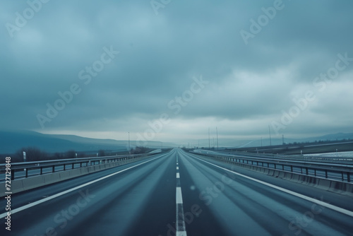 A gray cloudy sky with long stretch of highway.