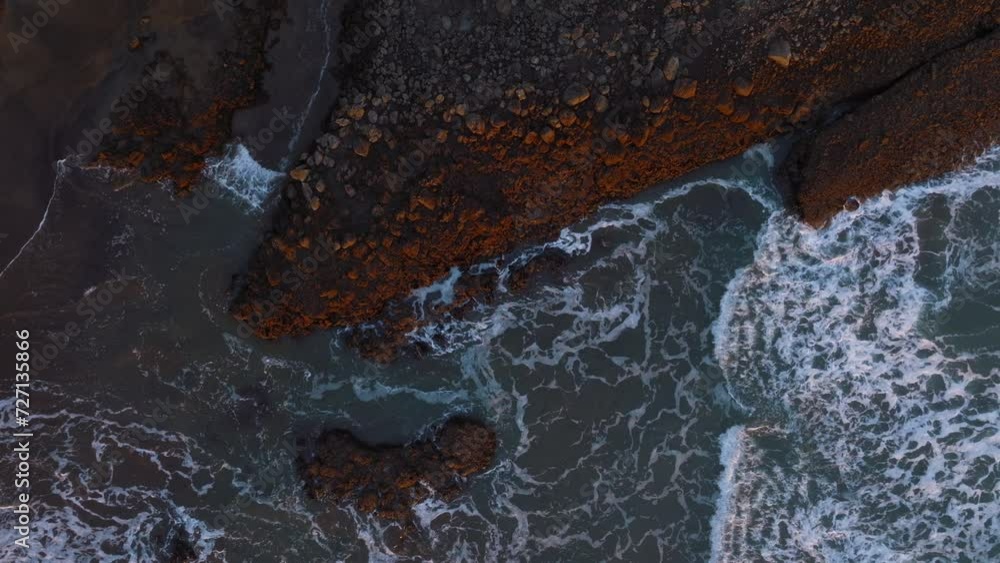 Aerial: Ocean waves crashing over rocks at sunset, Whites beach, Auckland, New Zealand. Aerial: Ocean waves crashing over rocks at sunset, Whites beach, Auckland, New Zealand.