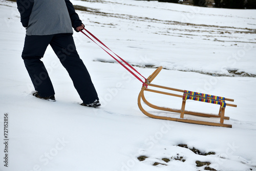Obraz na płótnie A man pulls a sledge up a hill in the winter tobogganing w salonie
