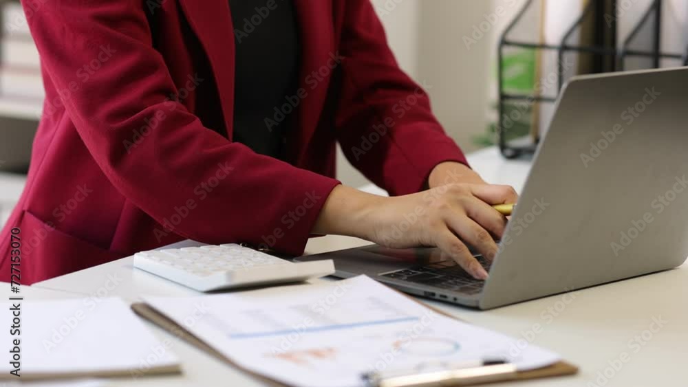 Accountant working on documents on laptop in office.