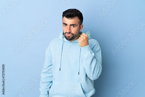 Caucasian man over isolated blue background with unhappy expression