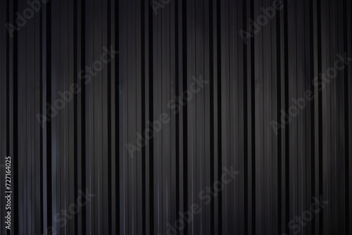 black corrugate wall background and texture,vertical black metal fence panel with light and shadow.