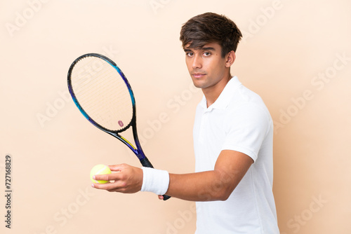 Young caucasian man isolated on ocher background playing tennis © luismolinero