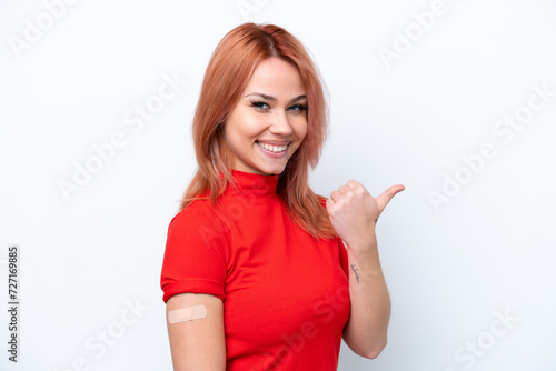 Young Russian girl wearing band-aids isolated on pink background pointing to the side to present a product