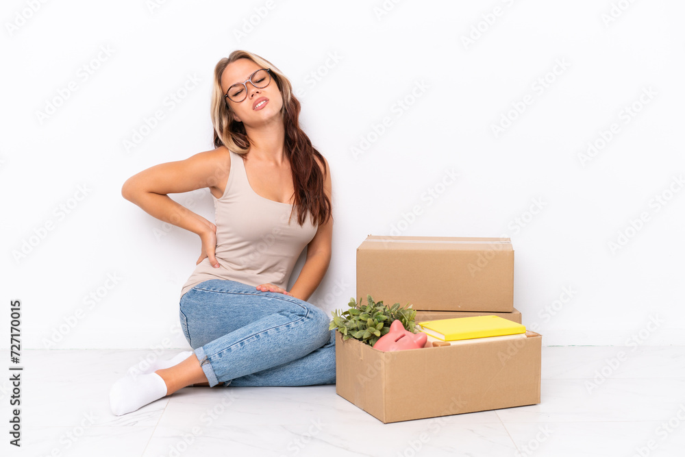 Young Russian girl sitting on the floor isolated on white background suffering from backache for having made an effort Young Russian girl sitting on the floor isolated on white background suffering from backache for having made an effort