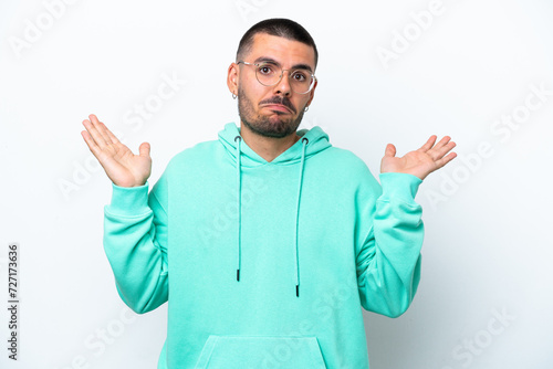 Young caucasian man isolated on white background making doubts gesture © luismolinero