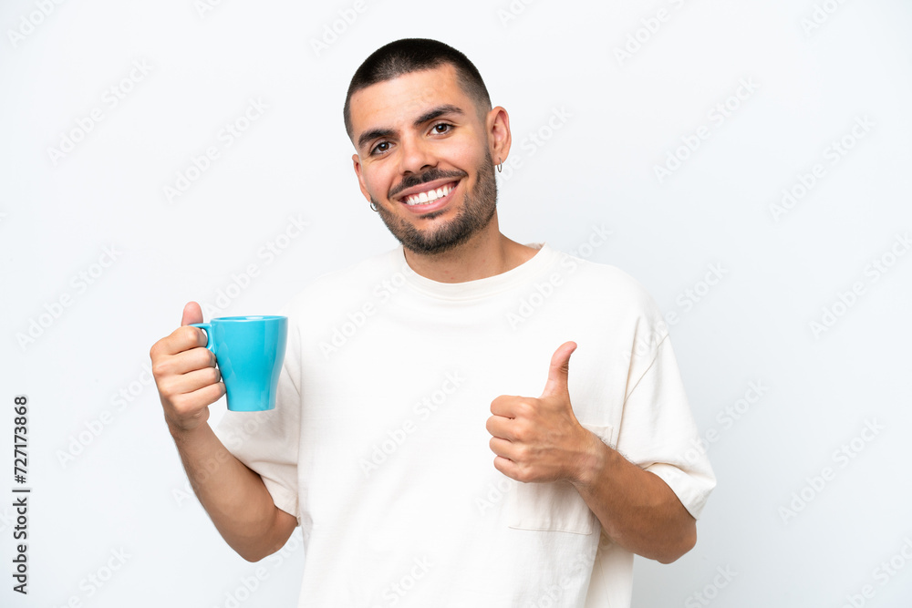 Young caucasian man holding cup of coffee isolated white background with thumbs up because something good has happened Young caucasian man holding cup of coffee isolated white background with thumbs up because something good has happened