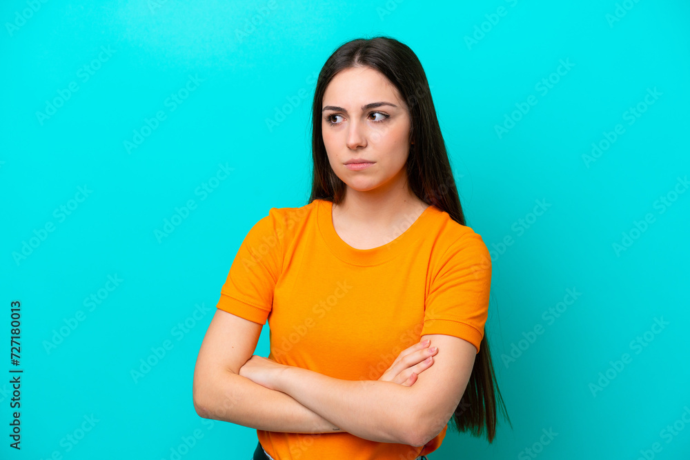 Obraz premium Young caucasian woman isolated on blue background keeping the arms crossed