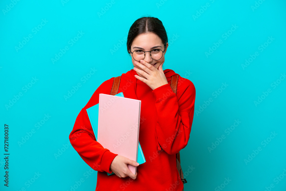 Young student caucasian woman isolated on blue background happy and smiling covering mouth with hand Young student caucasian woman isolated on blue background happy and smiling covering mouth with hand