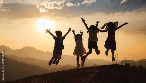 silhouette group of happy children jumping playing on mountain at sunset summer time