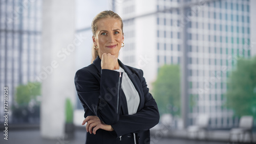 Portrait of an Adult Female in a Suit Posing for Camera, Smiling. Caucasian Businesswoman Standing in a Modern Office Space. Empowered CEO Ready to Manage a Successful Business Company