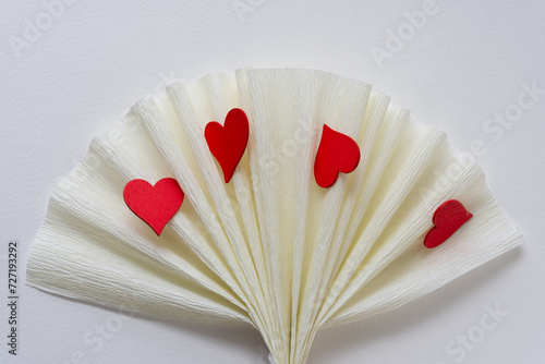fan-folded crepe paper and wooden hearts painted red on blank paper