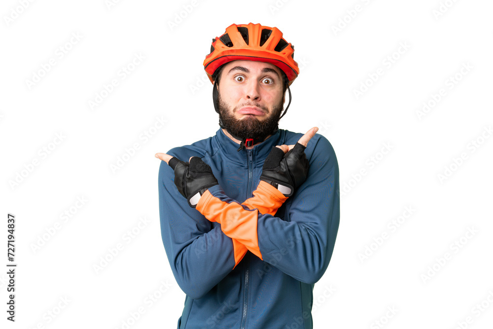 Young cyclist man over isolated chroma key background pointing to the laterals having doubts - obrazy, fototapety, plakaty 