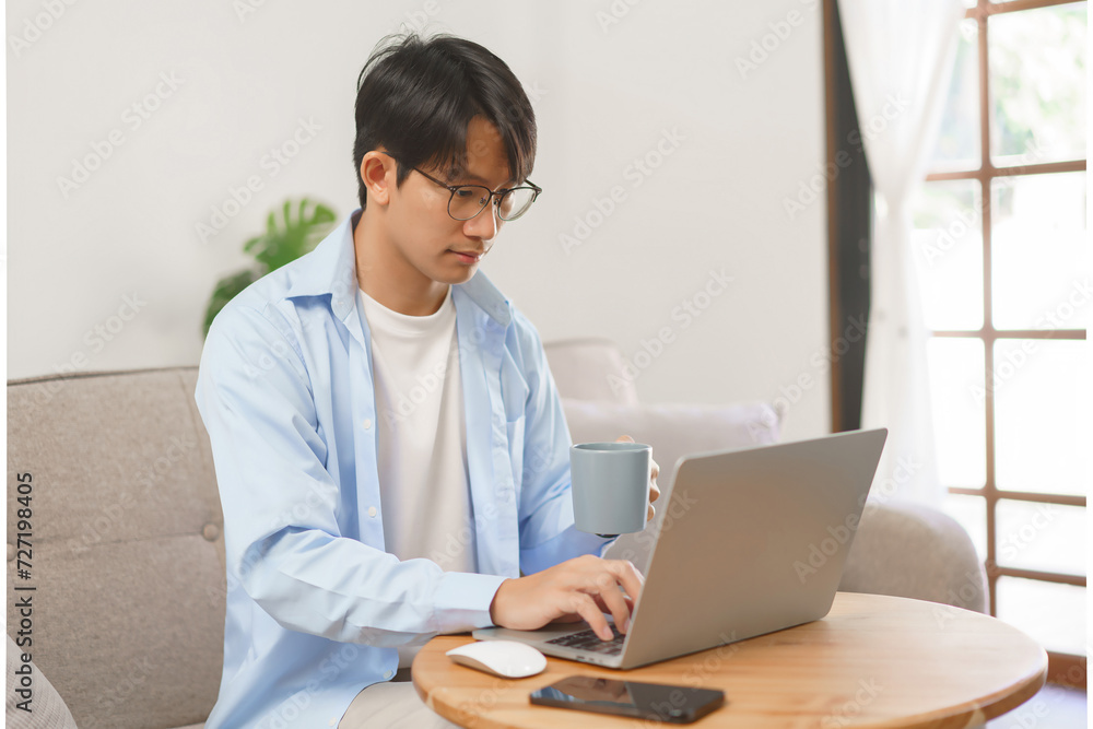 Business at home concept, Businessman drinking coffee in the morning and typing data on laptop Business at home concept, Businessman drinking coffee in the morning and typing data on laptop