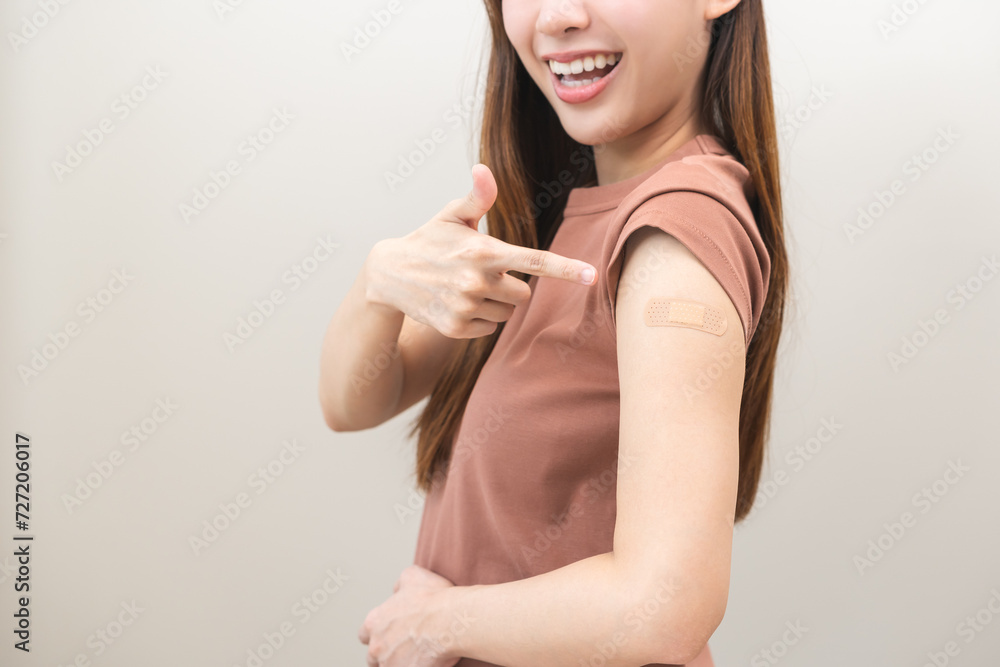 Obraz premium Healthcare of Covid-19, coronavirus vaccination, happy asian young woman hand pointing, showing at bandage, plaster on arm, getting vaccine immunity, giving injection influenza to protection pandemic.