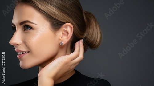 Jewelry concept. Portrait of beautiful young female model wearing silver earrings. Close-up of woman with clean skin posing, in studio background.