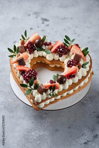 Honey cake decorated with fresh strawberries and herbs and cream cheese cream. Dessert for a loved one. Heart cake.