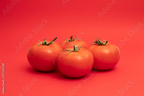 Four red tomato with a green stalk, on a red background. photo