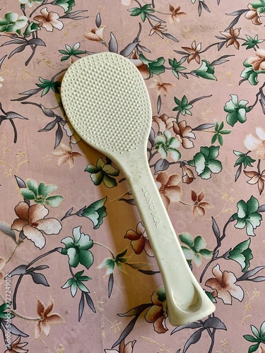 Old white rice spoon on floral patterned fabric.