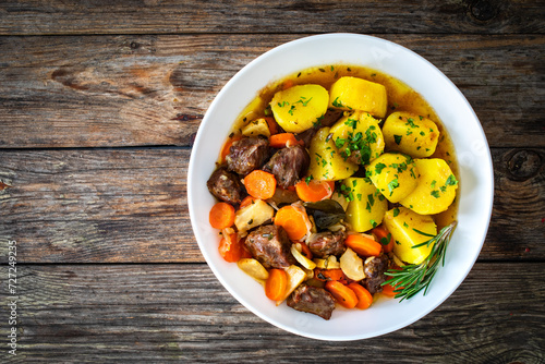 Roast pork cheeks with carrots and celeriac in sauce with boiled potatoes on wooden table  photo