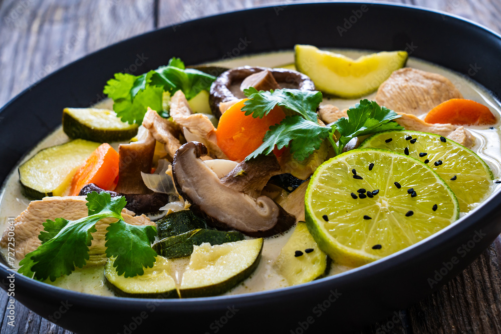 Tom Kha Gai soup - Thai soup with chicken breast nuggets and noodles on wooden table Tom Kha Gai soup - Thai soup with chicken breast nuggets and noodles on wooden table
