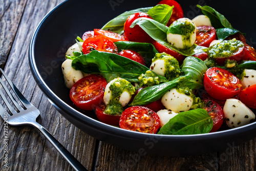 Caprese salad with pesto sauce on wooden board
 photo