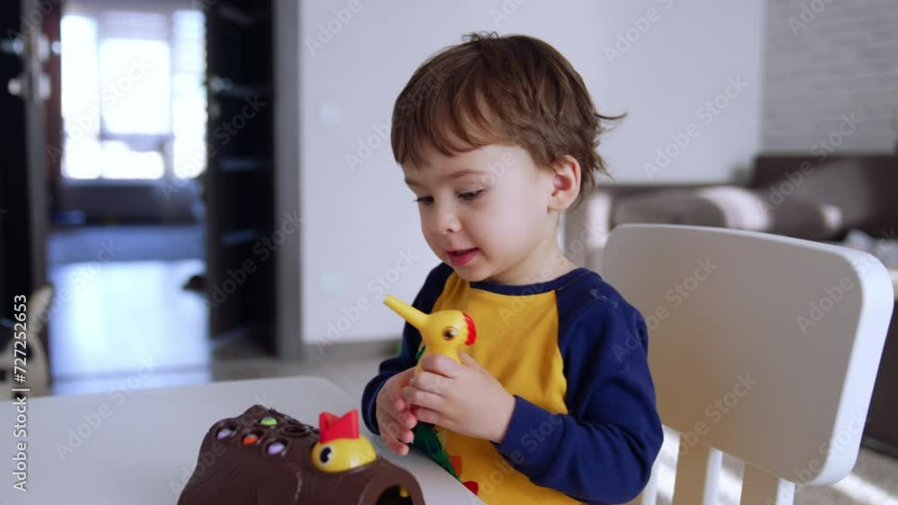 Cute baby boy sitting at the desk with a toy in front of him. Lovely baby playing at home. Close up. Cute baby boy sitting at the desk with a toy in front of him. Lovely baby playing at home. Close up.