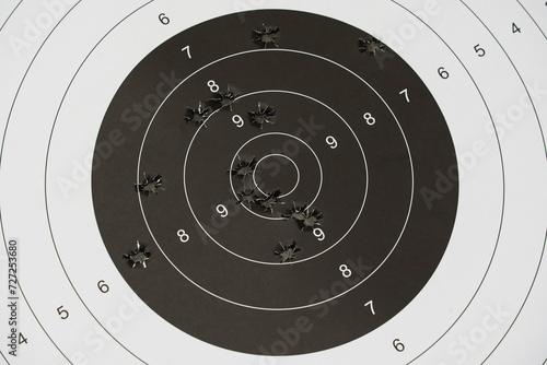 A paper target for shooting with holes from pistol bullets in the center, close-up photo.