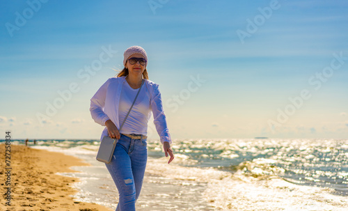 Beautiful mid adult woman walking on sunny beach 
