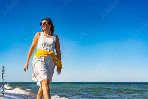Beautiful mid adult woman walking, running on sunny beach
