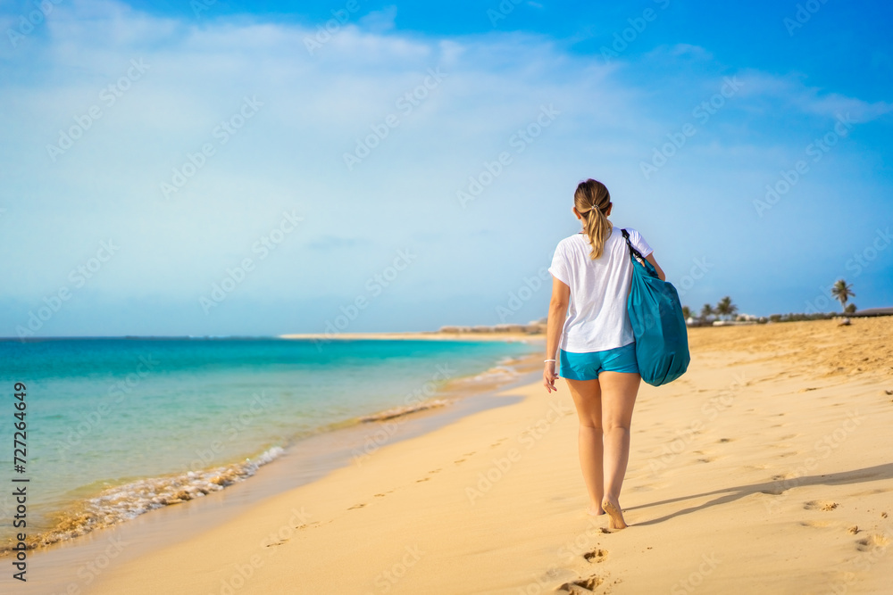 Beautiful woman walking on sunny beach Santa Maria, Sal Island, Cape Verde
