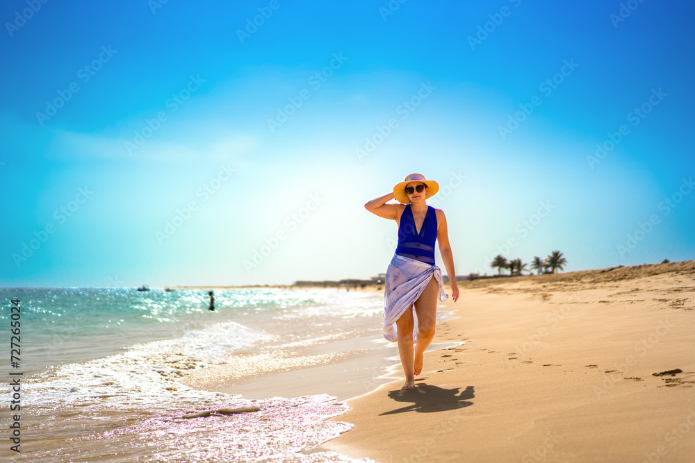 Beautiful woman walking on sunny beach Santa Maria, Sal Island, Cape Verde
