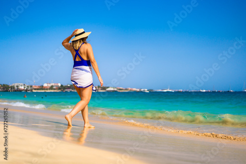 Beautiful woman walking on sunny beach Santa Maria, Sal Island, Cape Verde 