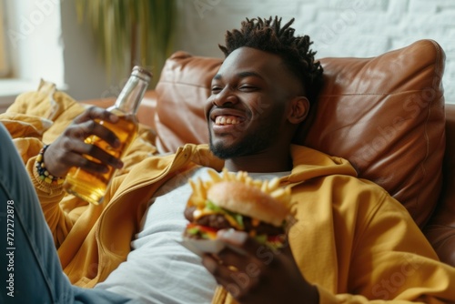 African American man enjoying fast food and entertainment at home. photo